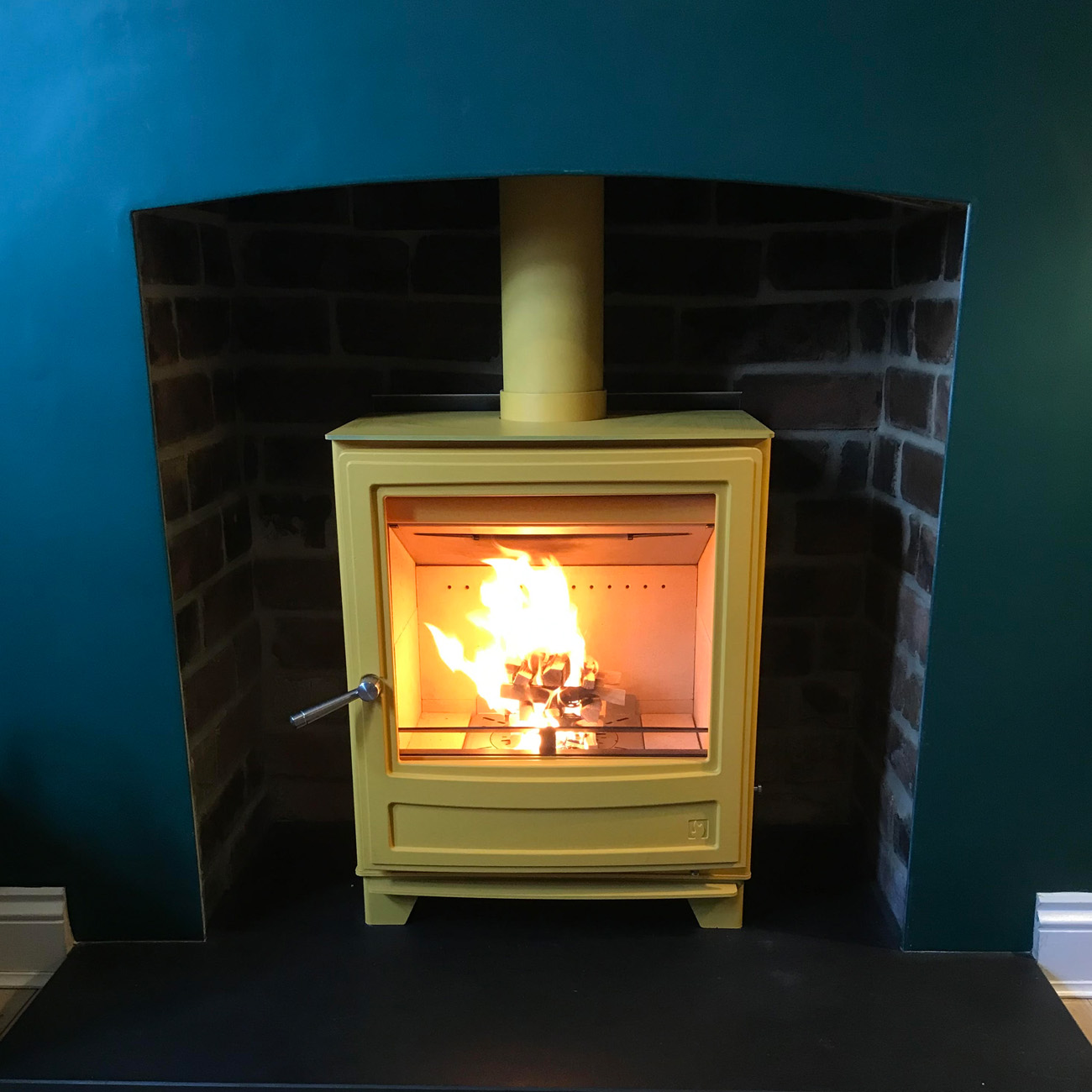 Cream stove fitted inside an opened fireplace by Firebug